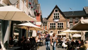 Menschen sitzen an heißen Sommertagen unter Sonnenschirmen in der belebten Aachener Innenstadt.
