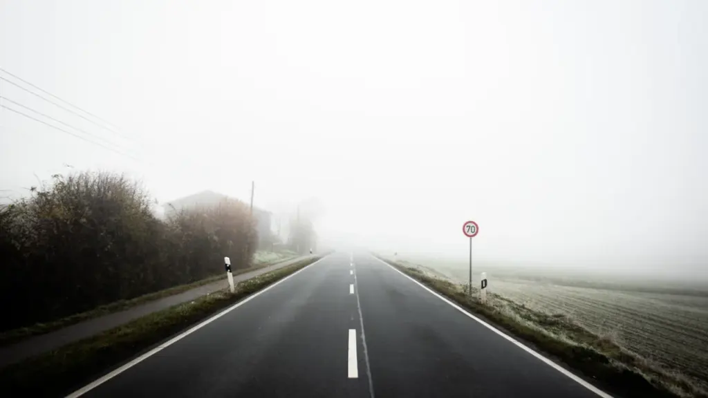 Eine neblige Landstraße in Deutschland mit einem Tempolimit-Schild am Straßenrand.