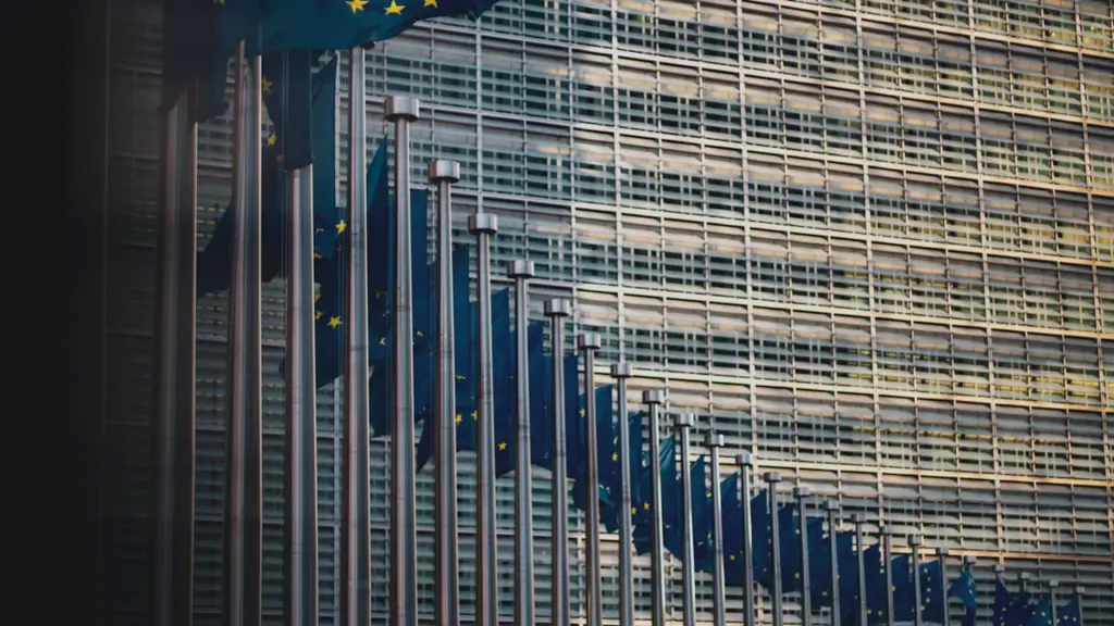 Europäische Flaggen vor dem Berlaymont-Gebäude der EU-Kommission in Brüssel bei Tageslicht.