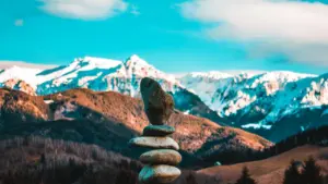 Ein gestapelter Steinturm vor einer beeindruckenden schneebedeckten Bergkulisse in der Natur.