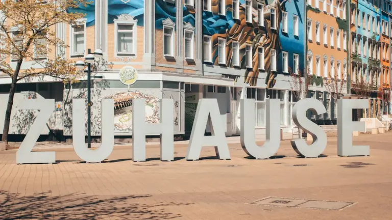 Große weiße Buchstaben auf dem Chemnitzer Brühl-Boulevard mit einem bunten Wohnhaus im Hintergrund.