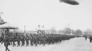 Historische Aufnahme einer Militärparade mit Luftschiff am Himmel während der Zwischenkriegszeit.