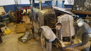 Ein restaurierungsbedürftiger Oldtimer in einer Werkstatt steht symbolisch für historische Fahrzeugtechnik und Geschichte.