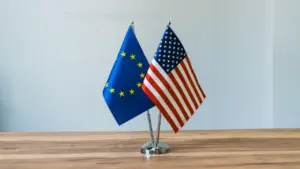 Kleine Flaggen der Europäischen Union und der Vereinigten Staaten stehen auf einem Holztisch.