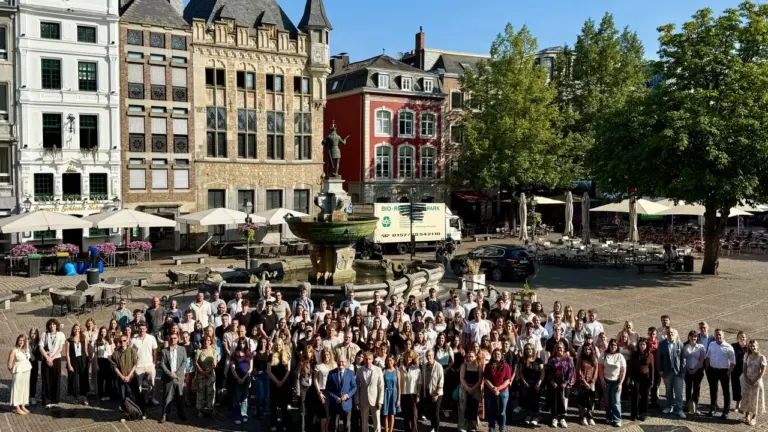 Eine große Menschengruppe posiert vor dem historischen Marktplatz-Brunnen in einer deutschen Altstadt.