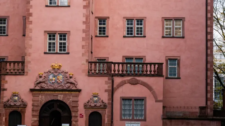 Historisches rosa Gebäude in Darmstadt mit prunkvollem Eingang und detailreichen Fenstern.