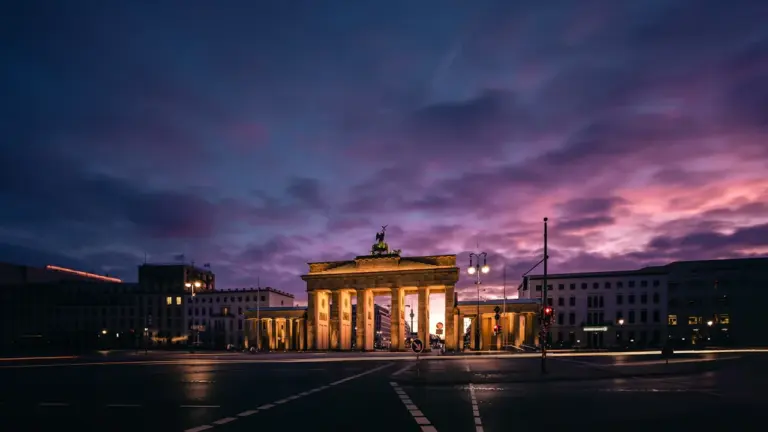 Das Brandenburger Tor in Berlin unter einem dramatischen, stimmungsvollen Abendhimmel im Licht.