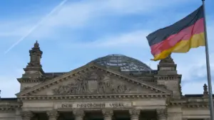 Die deutsche Flagge weht vor dem historischen Reichstagsgebäude unter einem strahlend blauen Himmel.