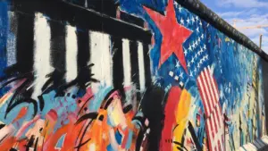 Ein Segment der Berliner Mauer mit künstlerischen Graffitis und historischer Symbolik.
