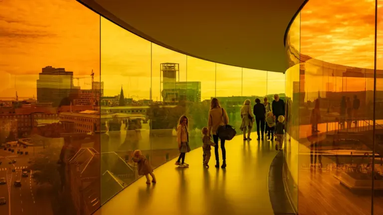 Menschen spazieren durch einen modernen, in warmes Licht getauchten architektonischen Gang.