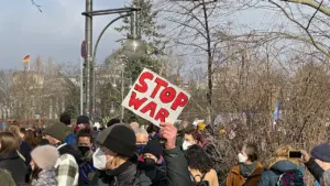 Menschenmenge bei einer Demonstration in Berlin mit einem Stop-War-Schild im Regierungsviertel.