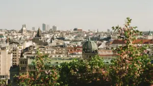 Blick über eine historische europäische Stadt mit architektonischen Details und blühenden Bäumen im Vordergrund.