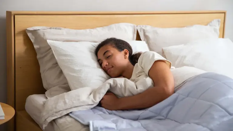 Eine junge Frau schläft friedlich in einem Bett mit heller Bettwäsche.