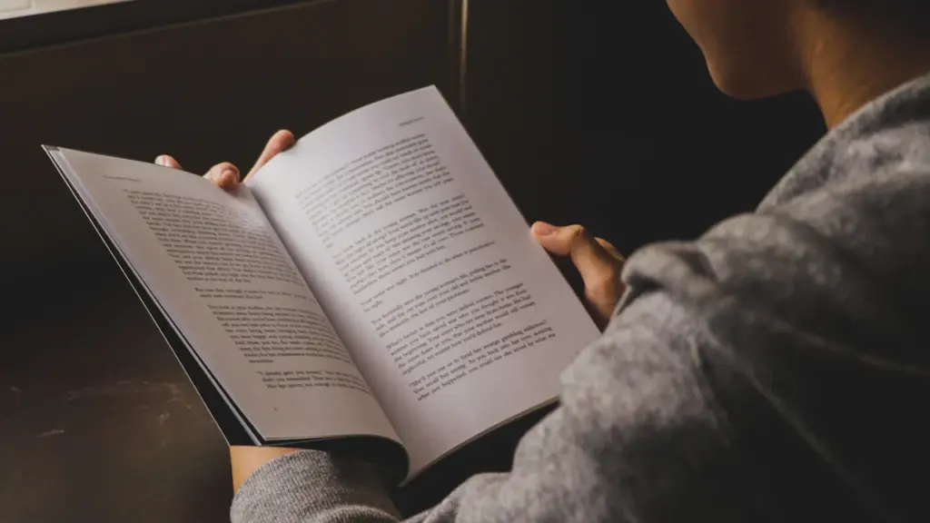 Eine Person liest konzentriert in einem Buch während eines entspannten Spaziergangs.