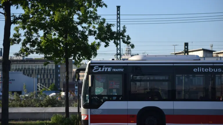 Ein rot-weißer Linienbus fährt auf einer deutschen Straße im täglichen Stadtverkehr.
