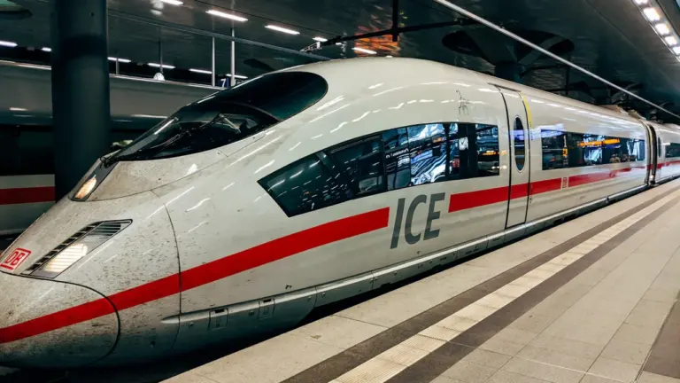 Ein ICE-Schnellzug steht abfahrbereit am Bahnsteig in einem deutschen Bahnhof.