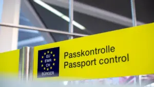 Gelbes Hinweisschild zur Passkontrolle an einem europäischen Flughafen bei der Einreise.