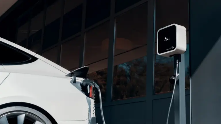 Ein weißes Elektroauto steht an einer Ladestation und wird mit Strom aufgeladen.