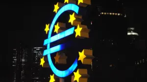 Die beleuchtete Euro-Skulptur vor einem Hochhaus bei Nacht in Frankfurt am Main.