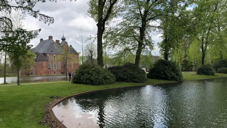 Ein historisches Gebäude am Ufer eines Weihers in einer städtischen Parkanlage.