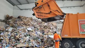 Ein Arbeiter in Warnkleidung entsorgt Müll in einem Betriebshof in Deutschland.