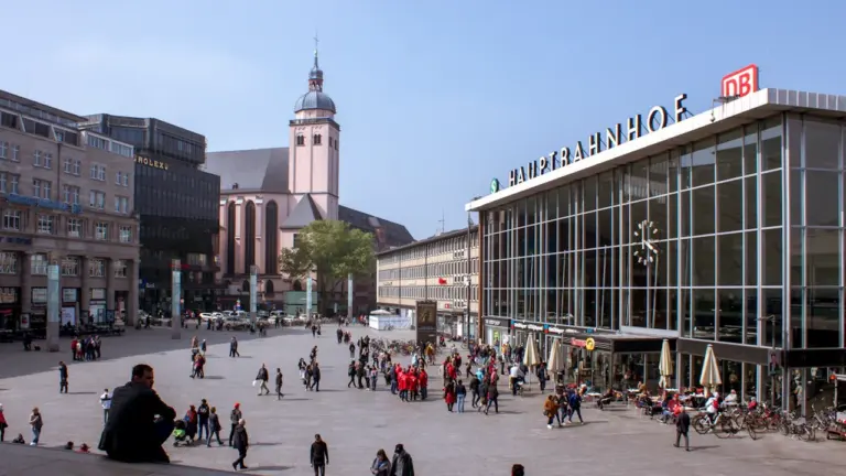 Der Kölner Hauptbahnhof bei Tageslicht mit Menschen auf dem Vorplatz.