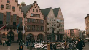 Menschen versammeln sich auf dem Frankfurter Römerberg vor historischen Fachwerkhäusern bei Tageslicht.