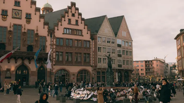 Menschen versammeln sich auf dem Frankfurter Römerberg vor historischen Fachwerkhäusern bei Tageslicht.