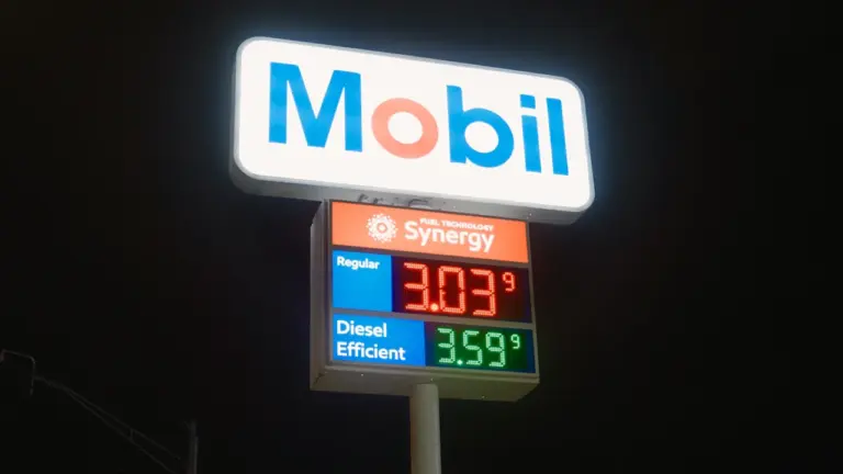 Eine beleuchtete Preistafel einer Tankstelle bei Nacht mit gut lesbaren digitalen Kraftstoffpreisen.