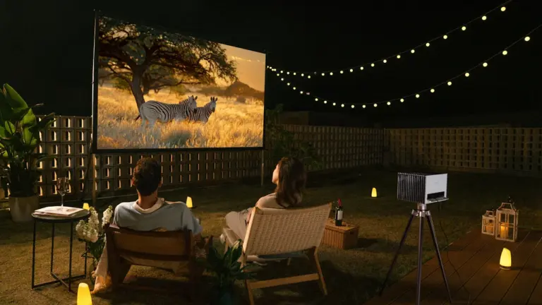 Paar genießt einen entspannten Filmabend bei Lichterketten in einem sommerlichen Garten in Deutschland.