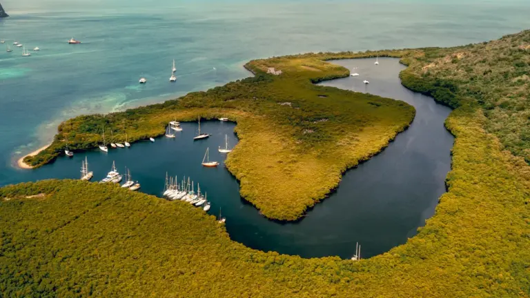 Luftaufnahme einer tropischen Bucht in der Karibik mit vor Anker liegenden Segelbooten.