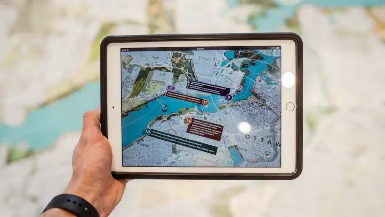 Hand hält ein Tablet mit einer digitalen Karte für die Stadtplanung.