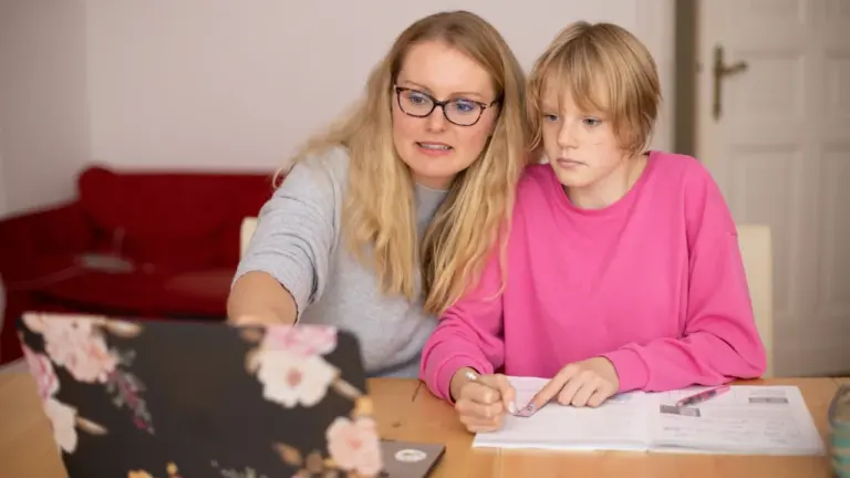 Mutter und Kind sitzen zu Hause vor dem Laptop bei den Hausaufgaben.
