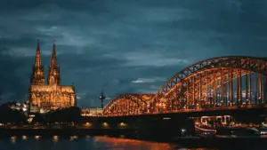 Nächtliche Ansicht des beleuchteten Kölner Doms und der Hohenzollernbrücke über dem Rhein.