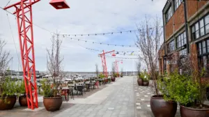 Moderne Hafenpromenade mit industriellem Charme, roten Kränen und gemütlichen Sitzgelegenheiten im Außenbereich.