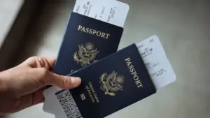 US-Reisepass mit Flugticket in der Hand eines Reisenden vor dem Flug.