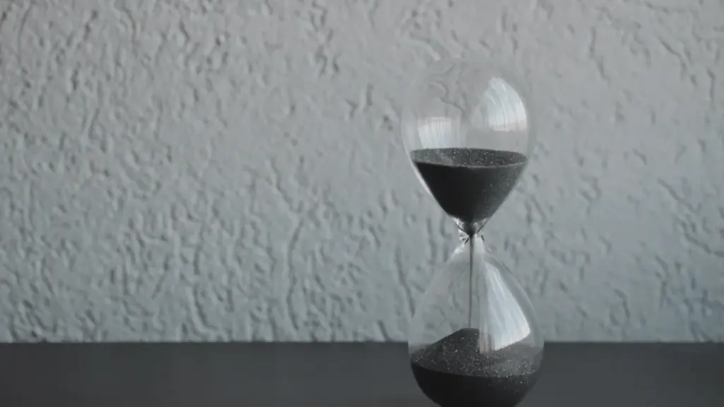 Eine Sanduhr mit blauem Sand am Strand, symbolisch für vergängliche Zeit und Achtsamkeit.