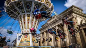 Buntes Kettenkarussell vor dem historischen Brandenburger Tor in der Berliner Innenstadt.