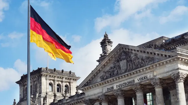 Die deutsche Flagge weht vor dem historischen Reichstagsgebäude in Berlin am helllichten Tag.