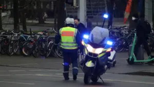 Ein deutscher Polizeibeamter auf einem Motorrad bei einer Verkehrskontrolle im städtischen Raum.