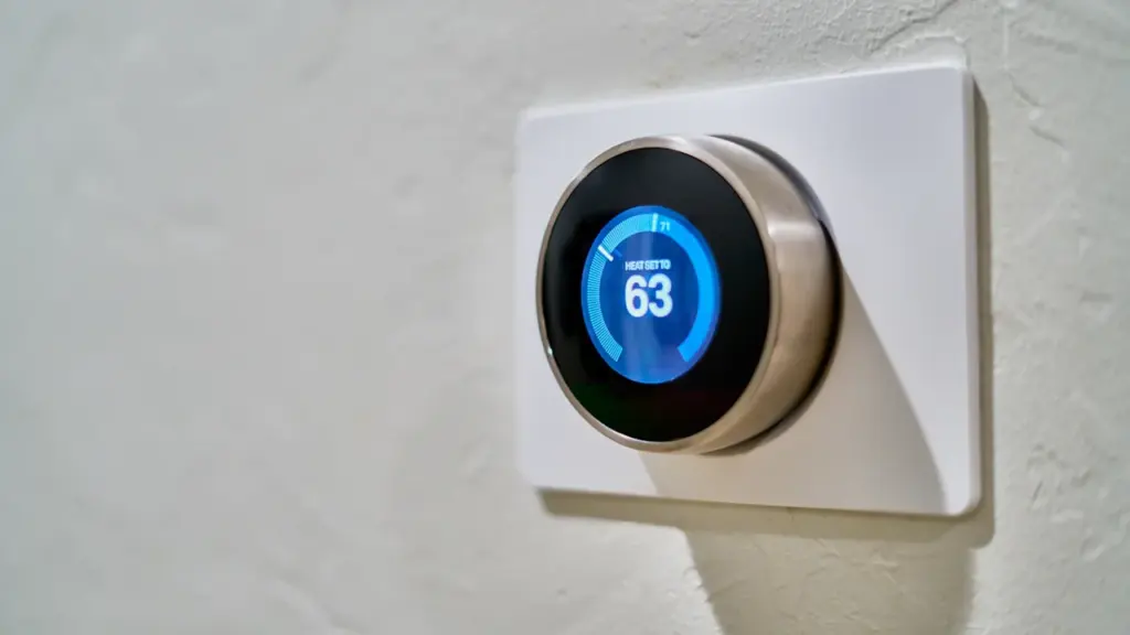 Modernes smartes Thermostat an einer hellen Wand zur Steuerung der Raumtemperatur im Winter.