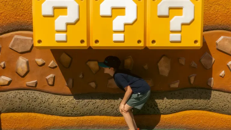 Kind steht unter großen gelben Fragezeichen-Blöcken, bekannt aus dem Videospiel Mario Kart.