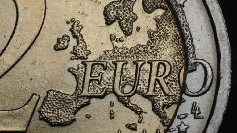 Euromünzen auf weißem Untergrund, darunter eine 2-Euro-Münze mit dem Brandenburger Tor.
