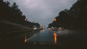 Autoverkehr auf einer regennassen Autobahn unter einem grauen, bewölkten Himmel.